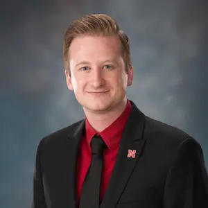 Profile photo of Kevin Abel wearing a black suit and red shirt